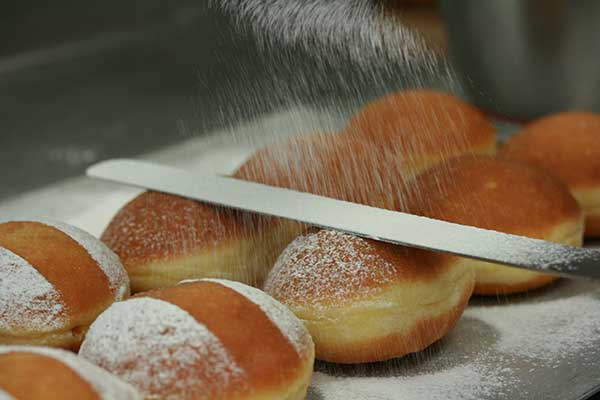 Krapfen werden mit Staubzucker bestreut.